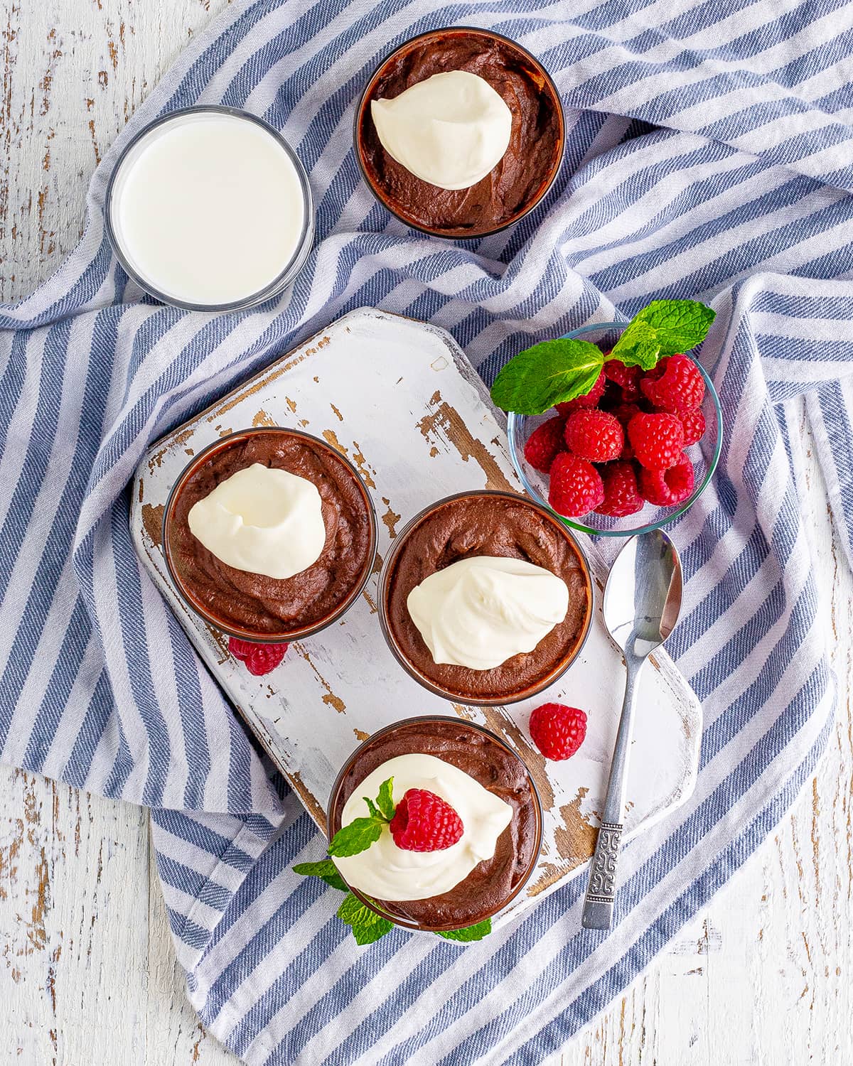 An overhead photo of four bowls of easy chocolate mousse with whipped cream on them.