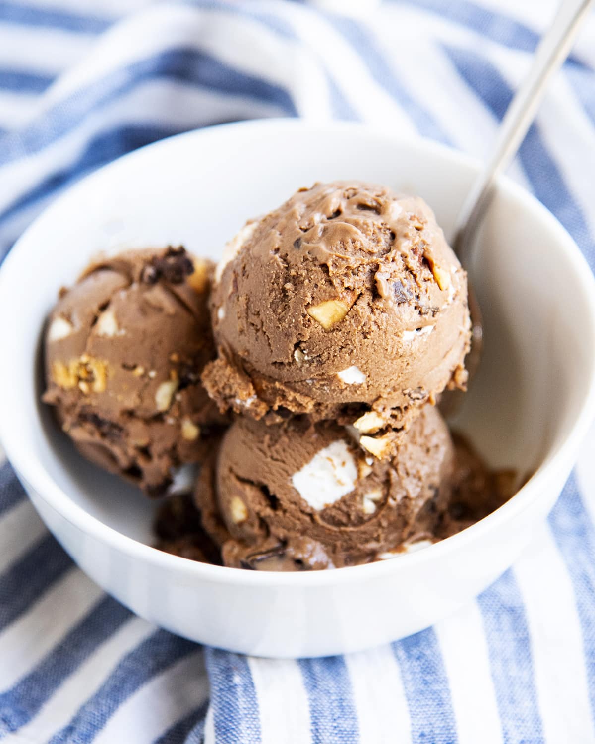 A bowl full of three scoops of chocolate rocky road ice cream.