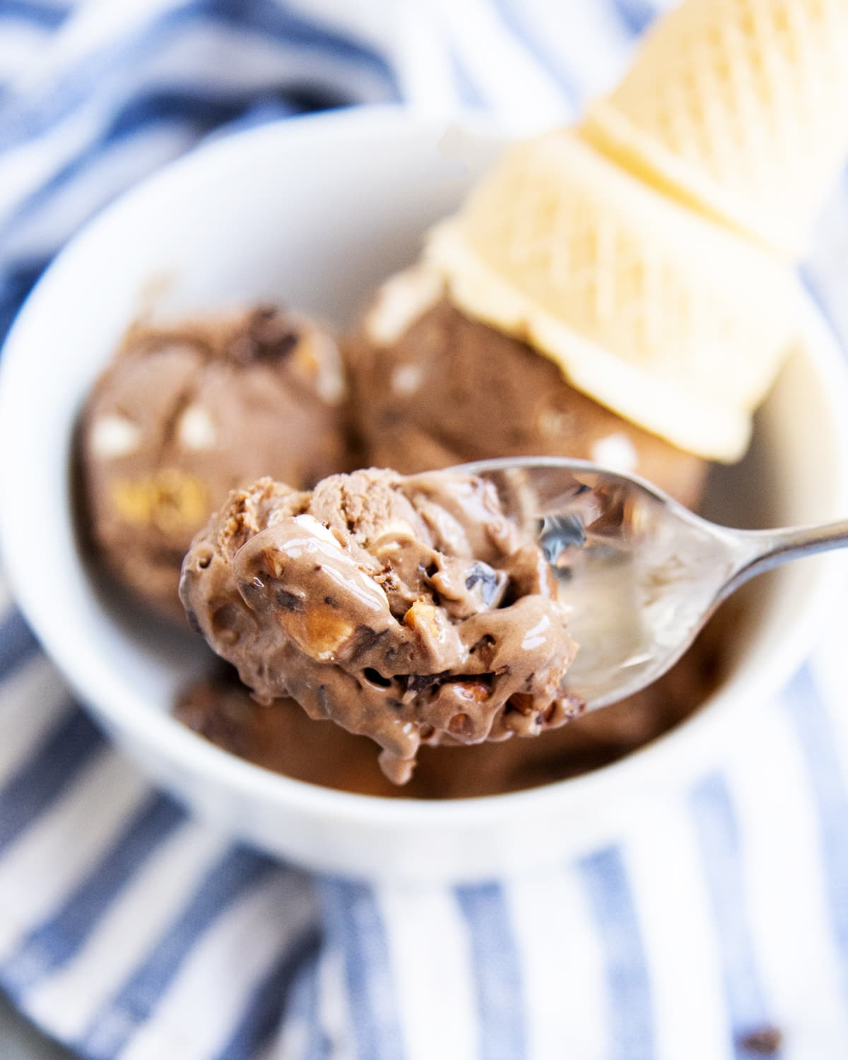 A spoonful of rocky road chocolate ice cream above a bowl of it.