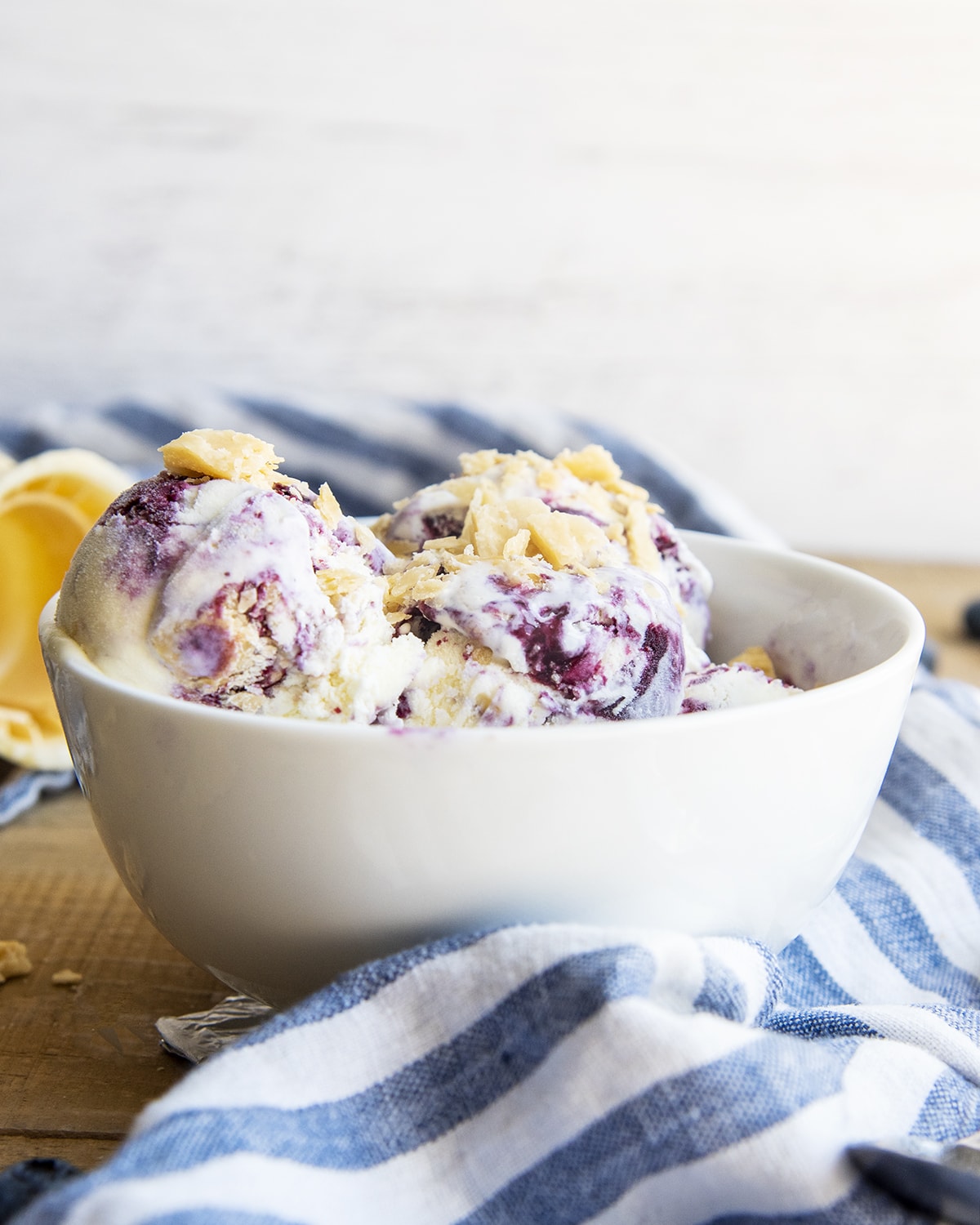 A bowl of blueberry pie ice cream, with pie crust crumbles on top.