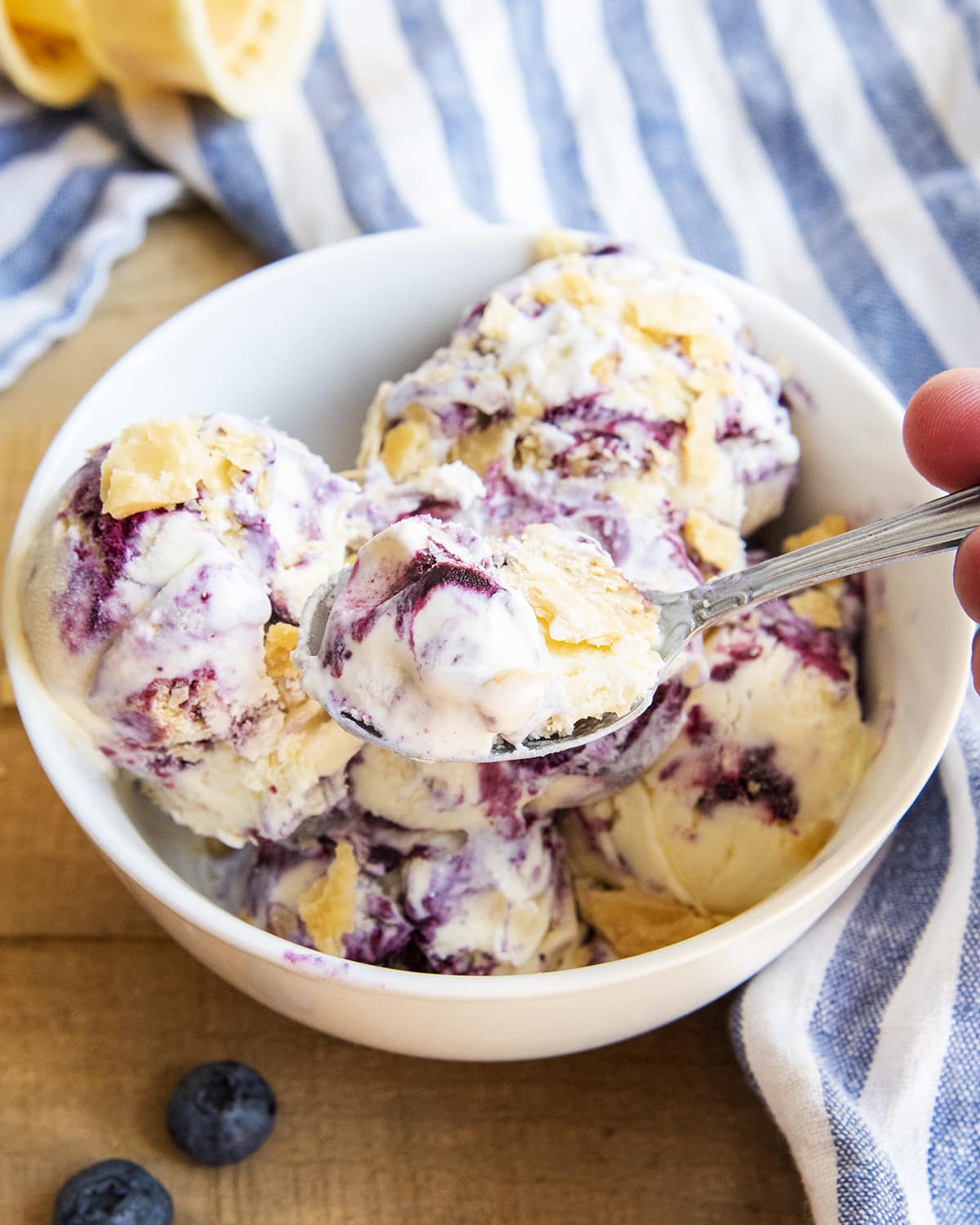 A bowl of blueberry pie ice cream with pie crust pieces crumbled on top.