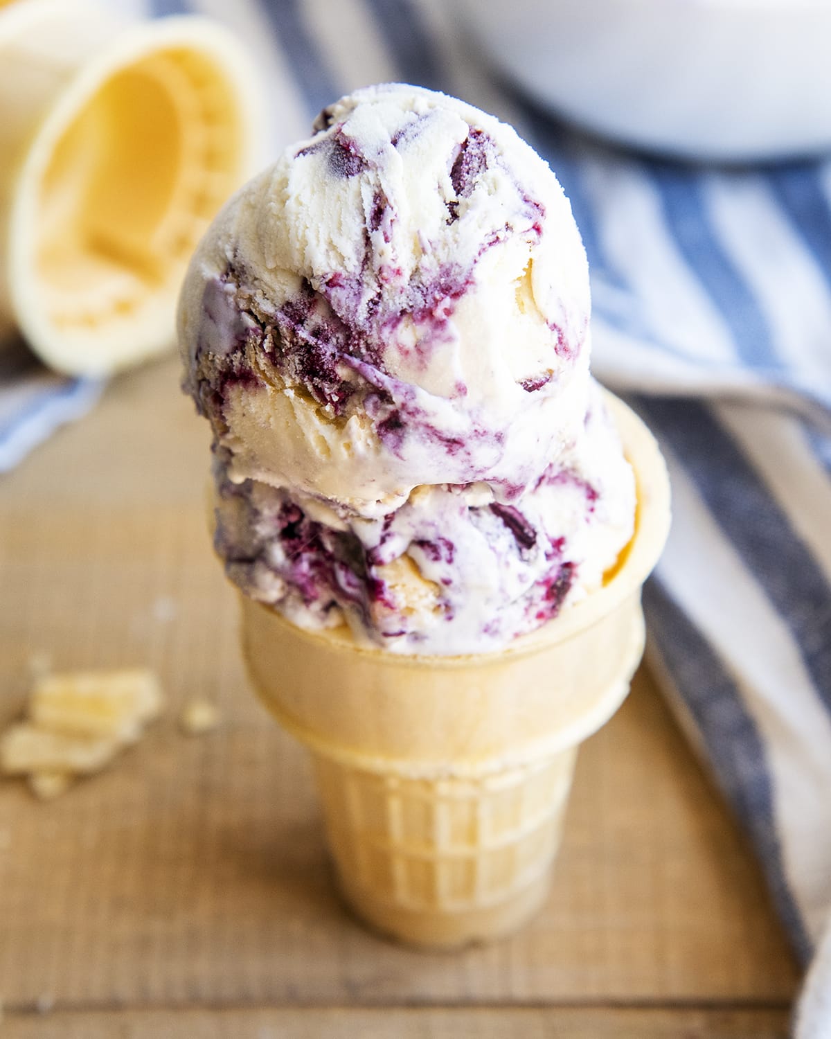 A close up of a blueberry pie ice cream cone with two scoops of ice cream.