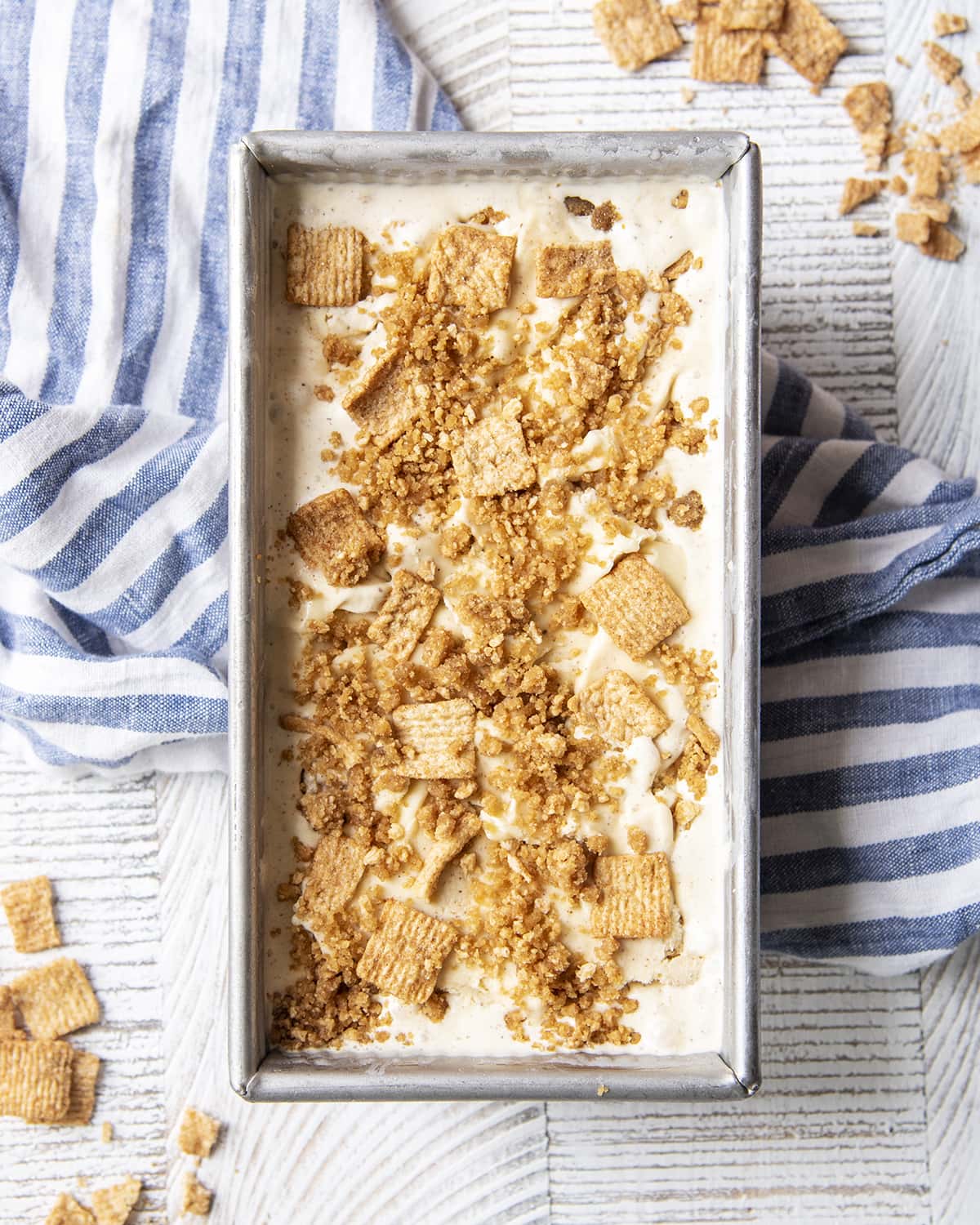 A bread pan filled with a white ice cream topped with cinnamon toast crunch cereal.