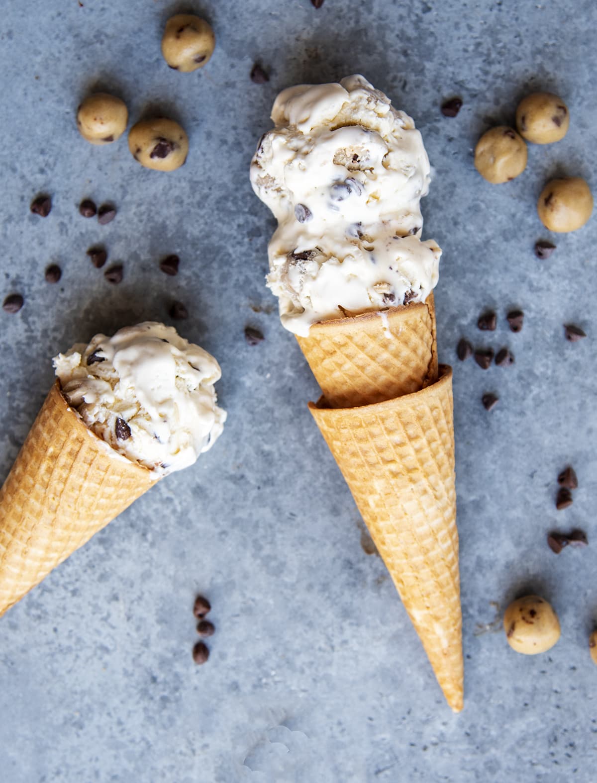 Two cones of chocolate chip cookie dough ice cream laying on a counter top.