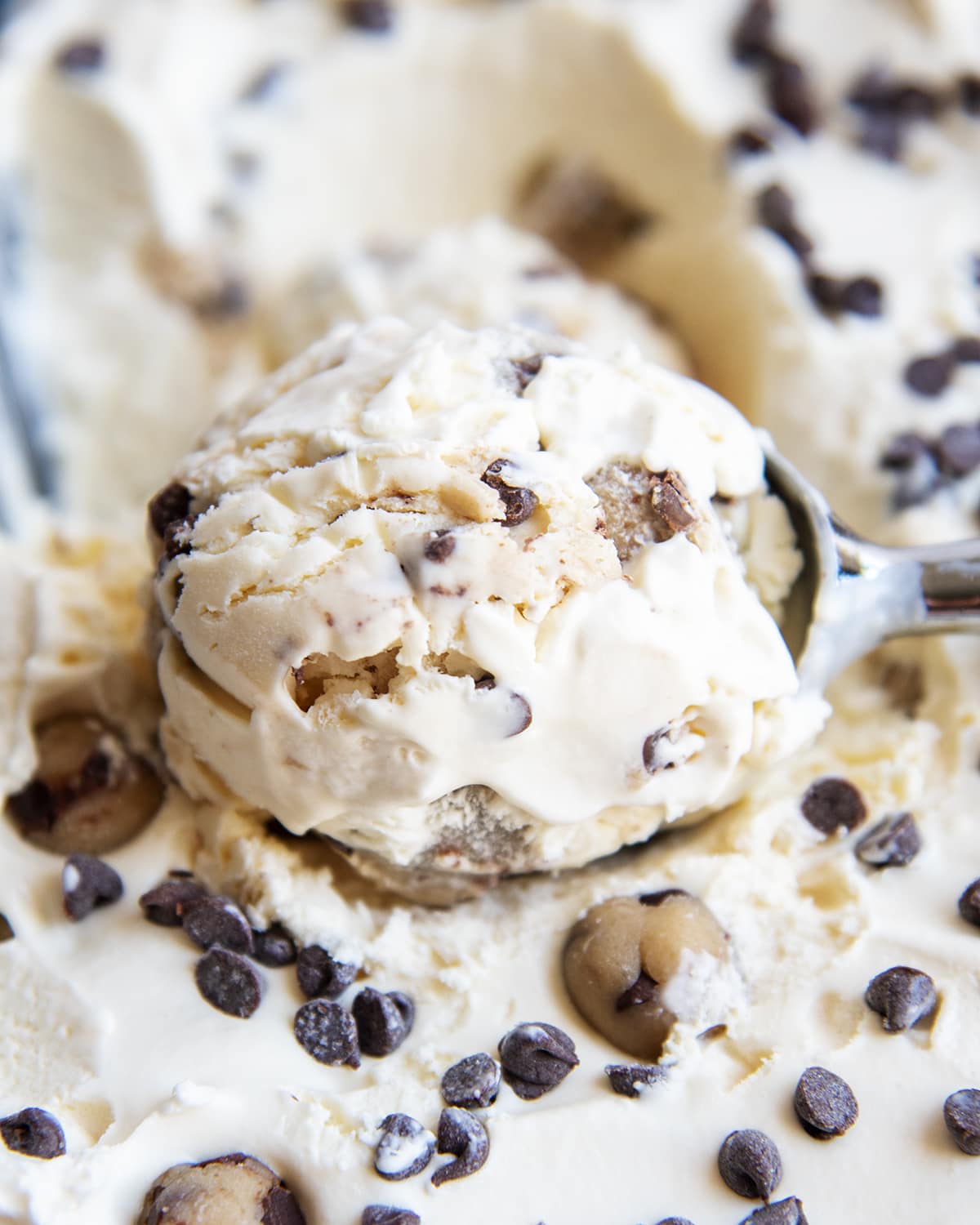 A close up of a scoop of cookie dough ice cream with chocolate chips in it.
