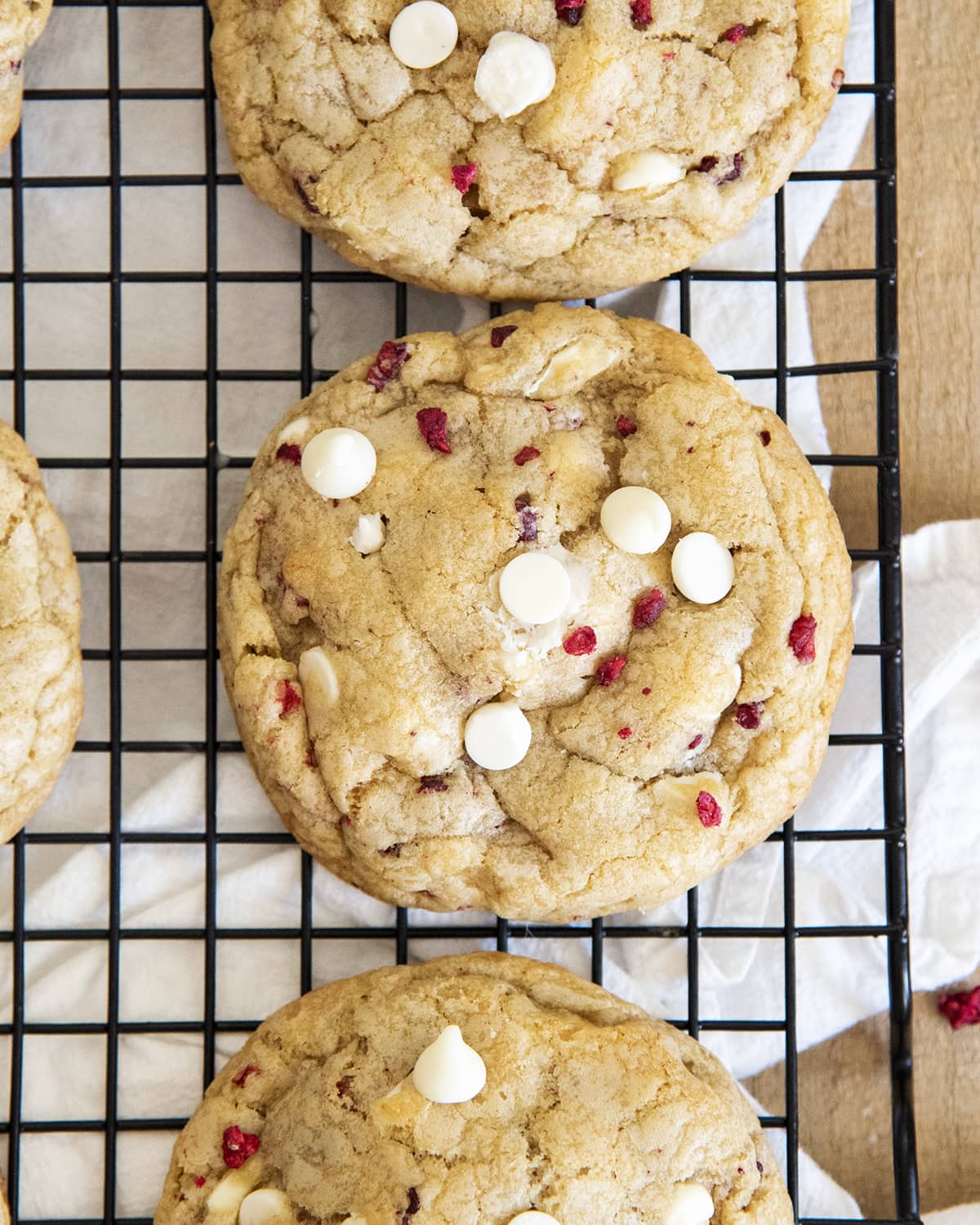A cooling rack topped with big cookies full of freeze dried raspberries and white chocolate chips.
