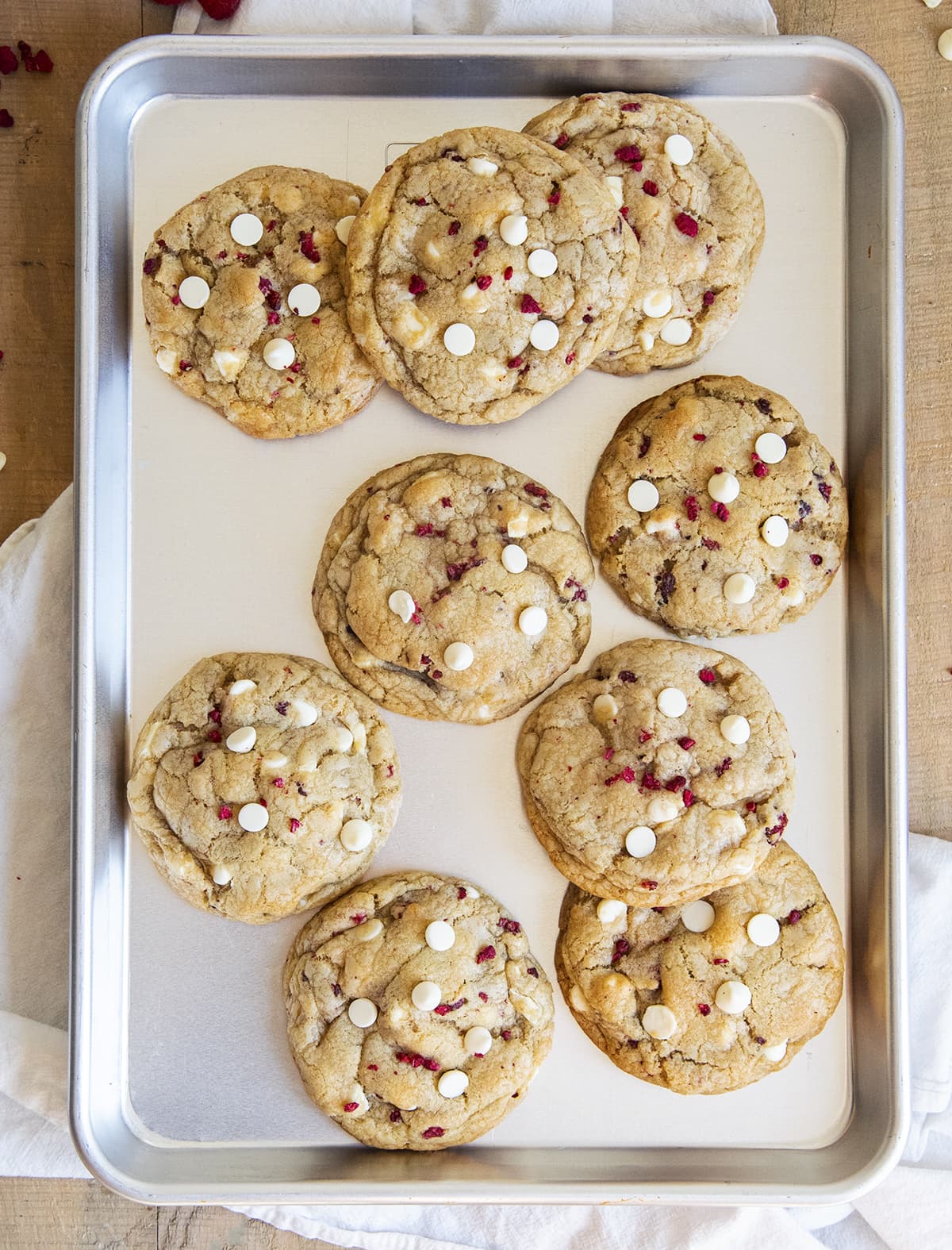 A cookie sheet covered in large raspberry and white chocolate cookies.