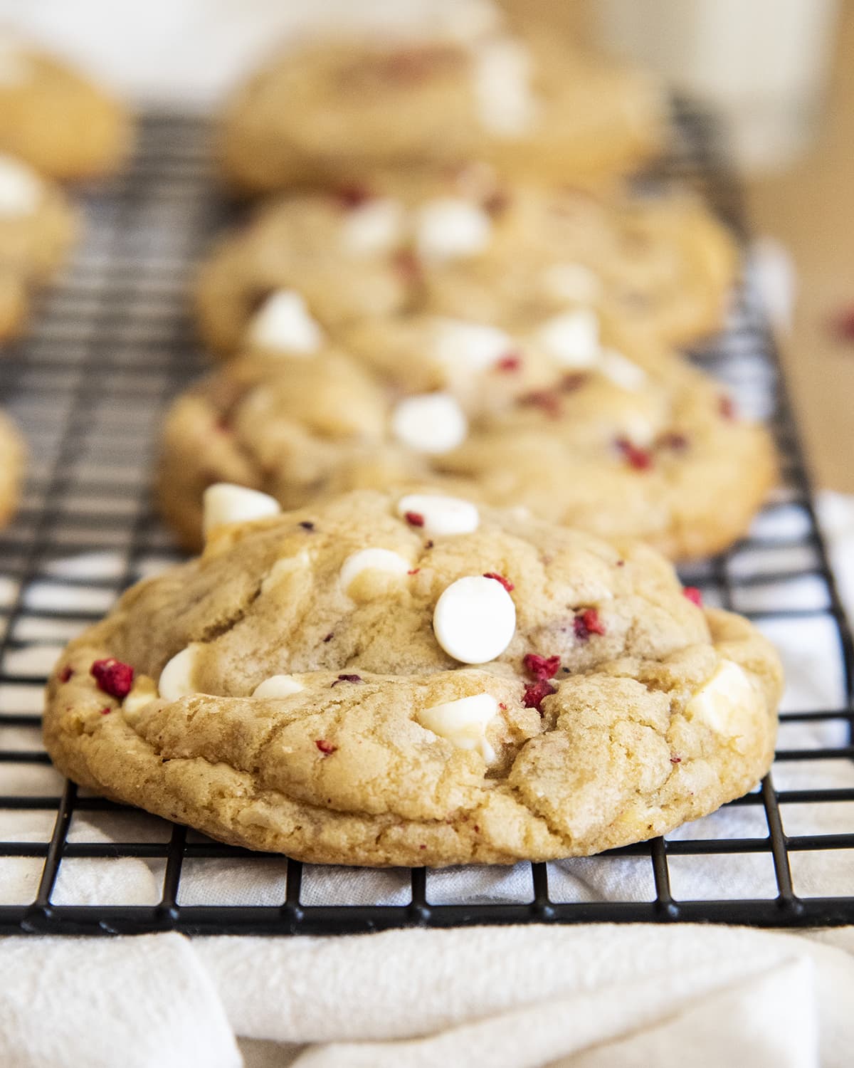 A close up of a white chocolate raspberry cookie on a cooling rack. 