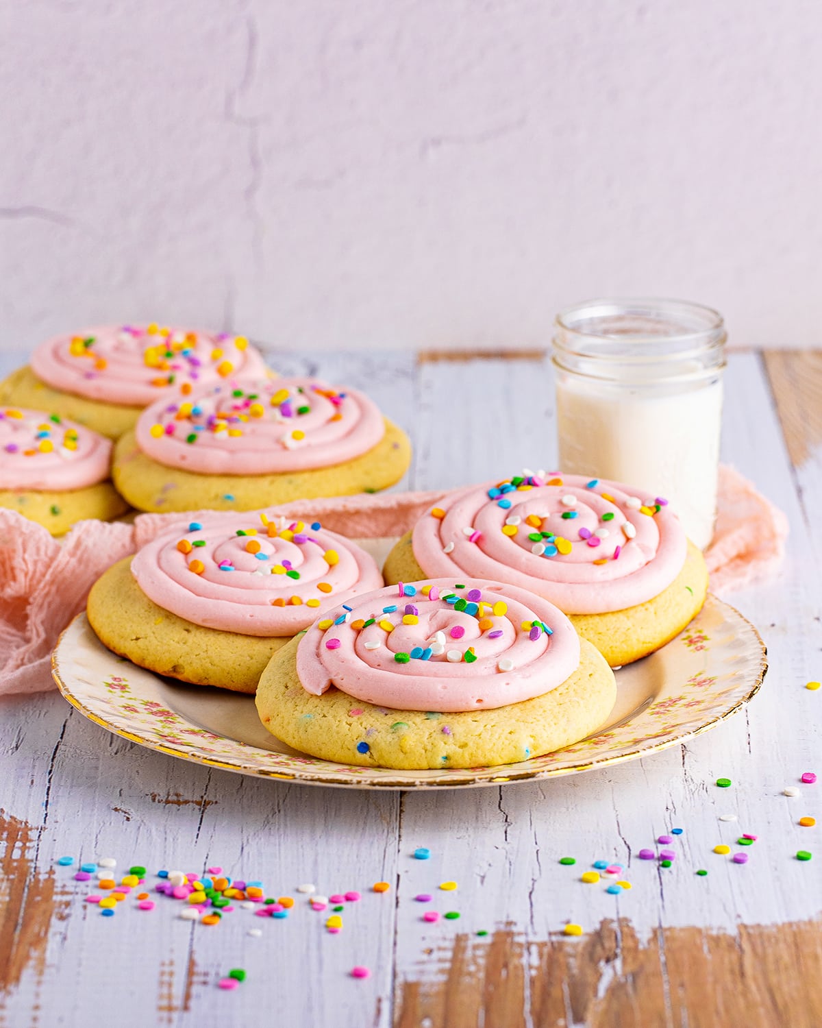 A plate of Crumbl copycat Confetti cake cookies with pink frosting on them.