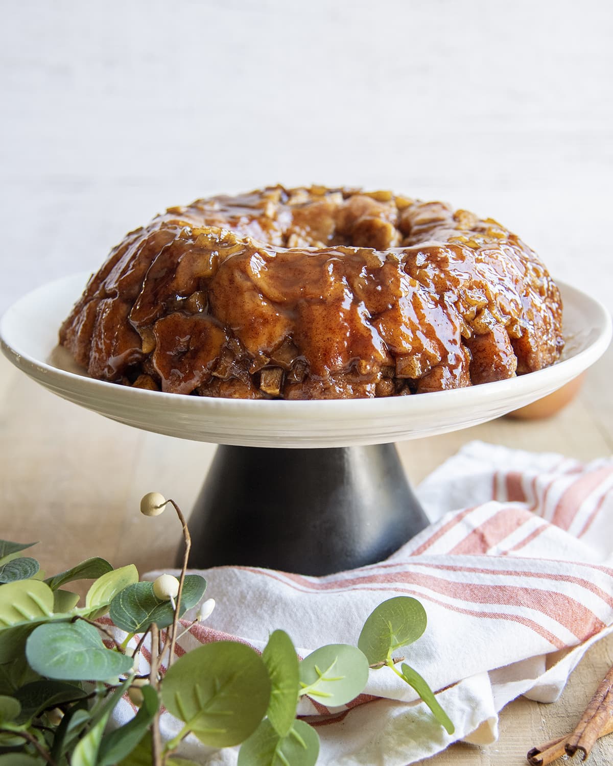Apple monkey bread on a cake stand with greenery around it.