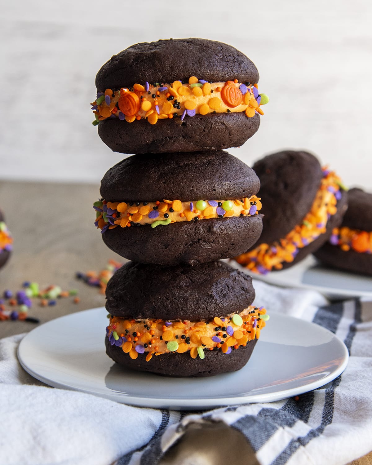 A stack of three Halloween whoopie pie cookie sandwiches on a plate.