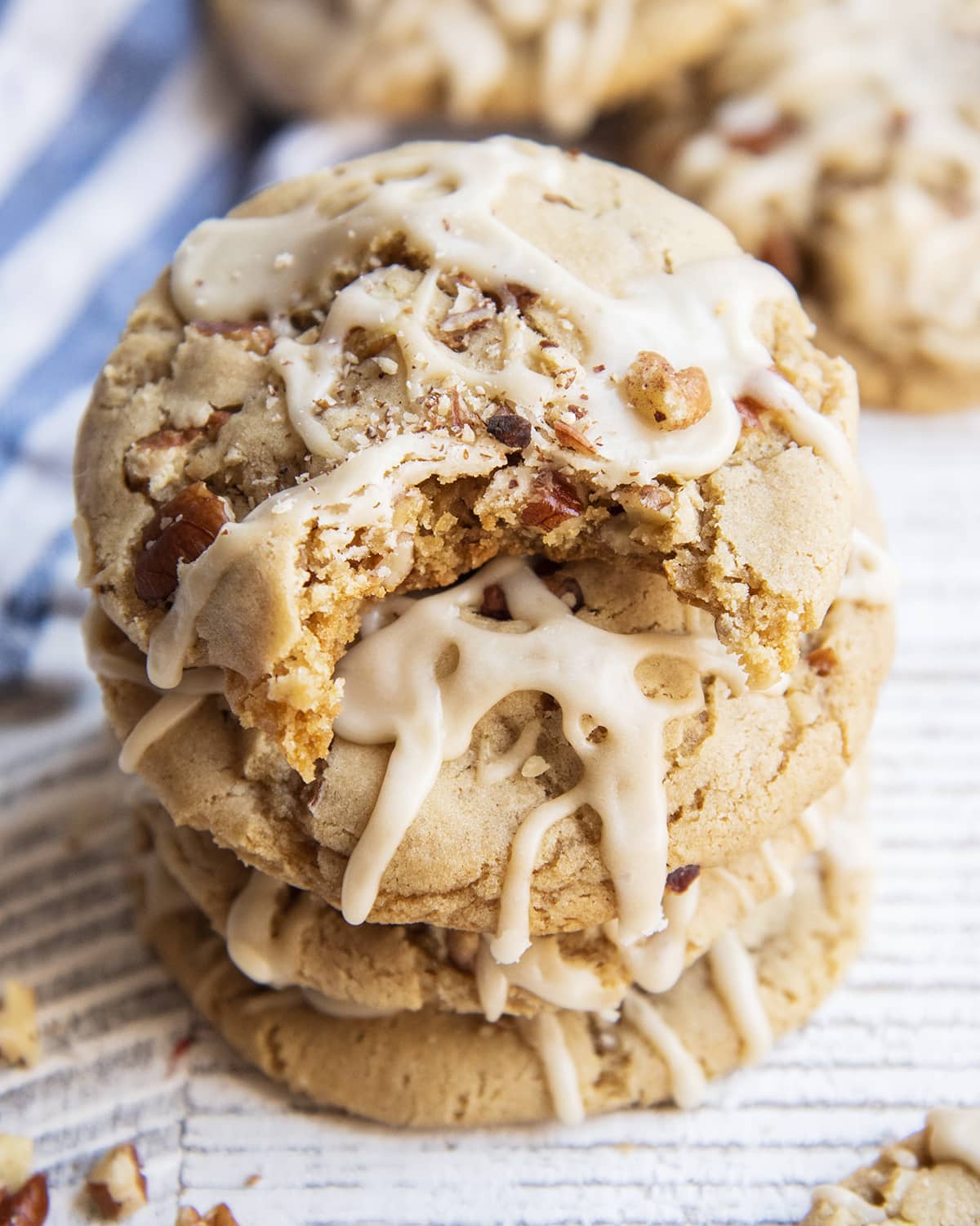 A stack of four maple pecan cookies, and the top cookie has a bite out of it.