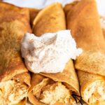A plate of pumpkin crepes filled with pumpkin cheesecake filling with a text block over the top for pinterest.