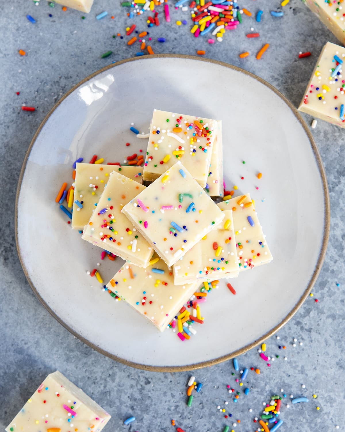 An overhead photo of a plate of funfetti fudge pieces full of of rainbow sprinkles.