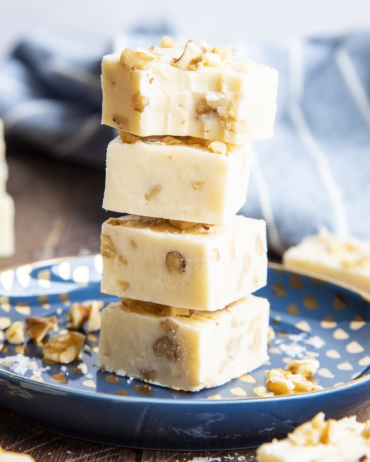 A stack of maple walnut fudge pieces, the top piece has a bite out of it.