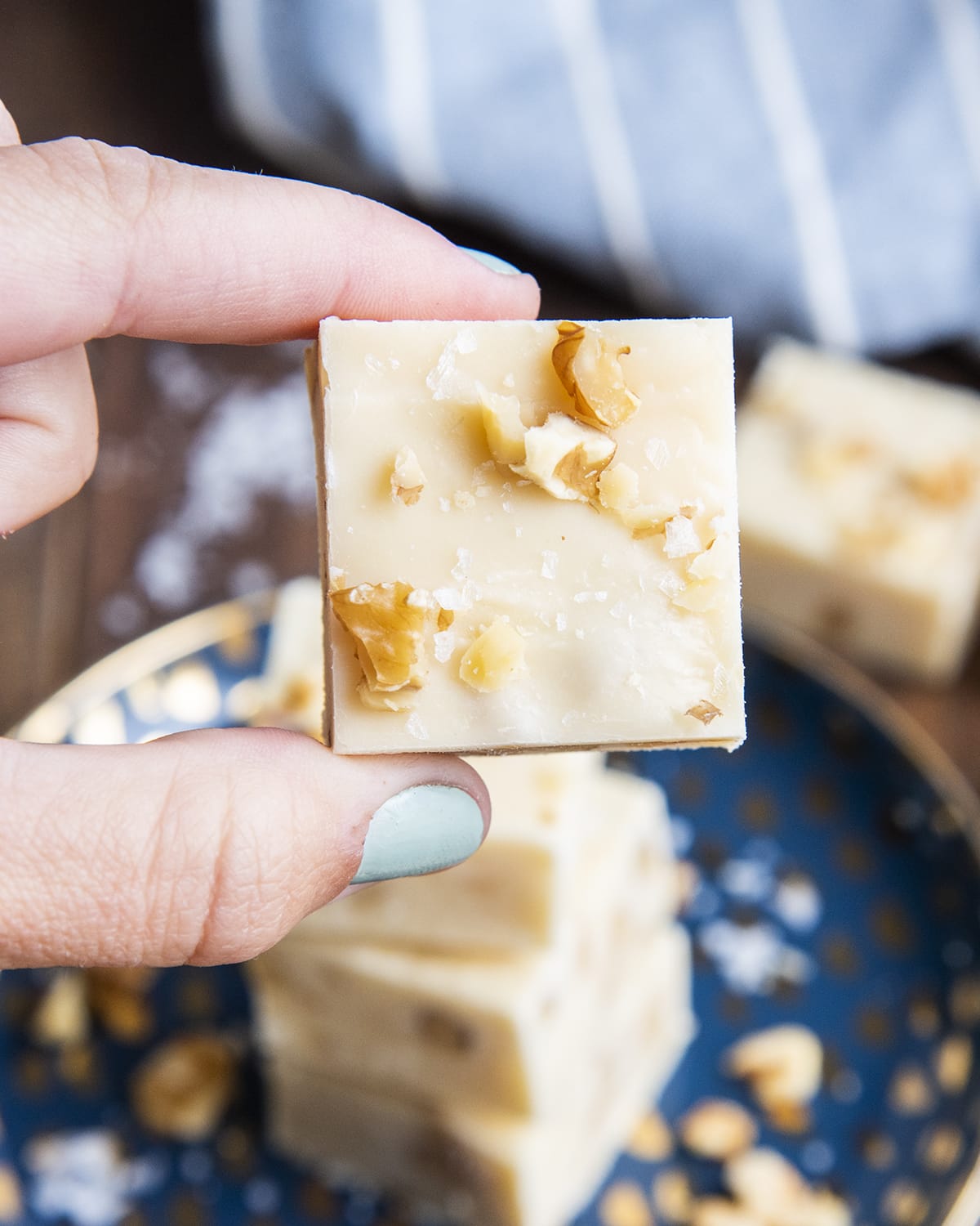 A hand holding a piece of maple walnut fudge.
