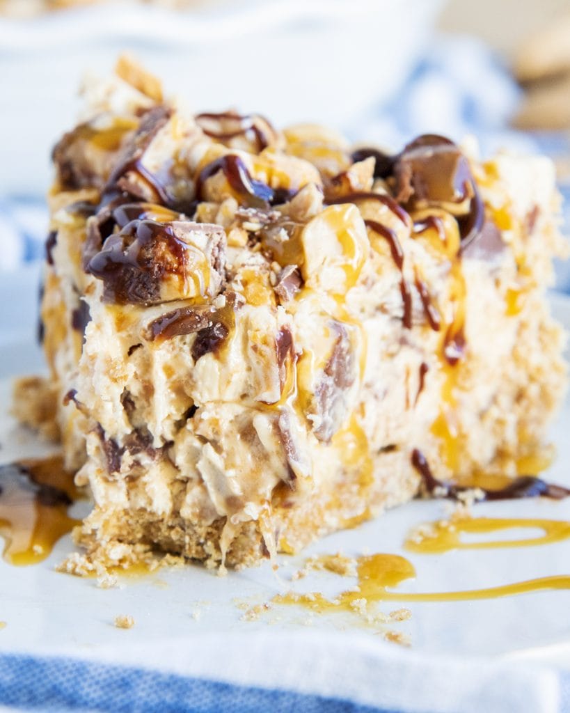 A close up of a slice of snickers pie with a bite taken out of the front.