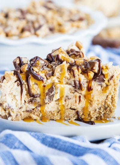 The side view of a thick piece of no bake snickers pie with snickers and caramel syrup on top.