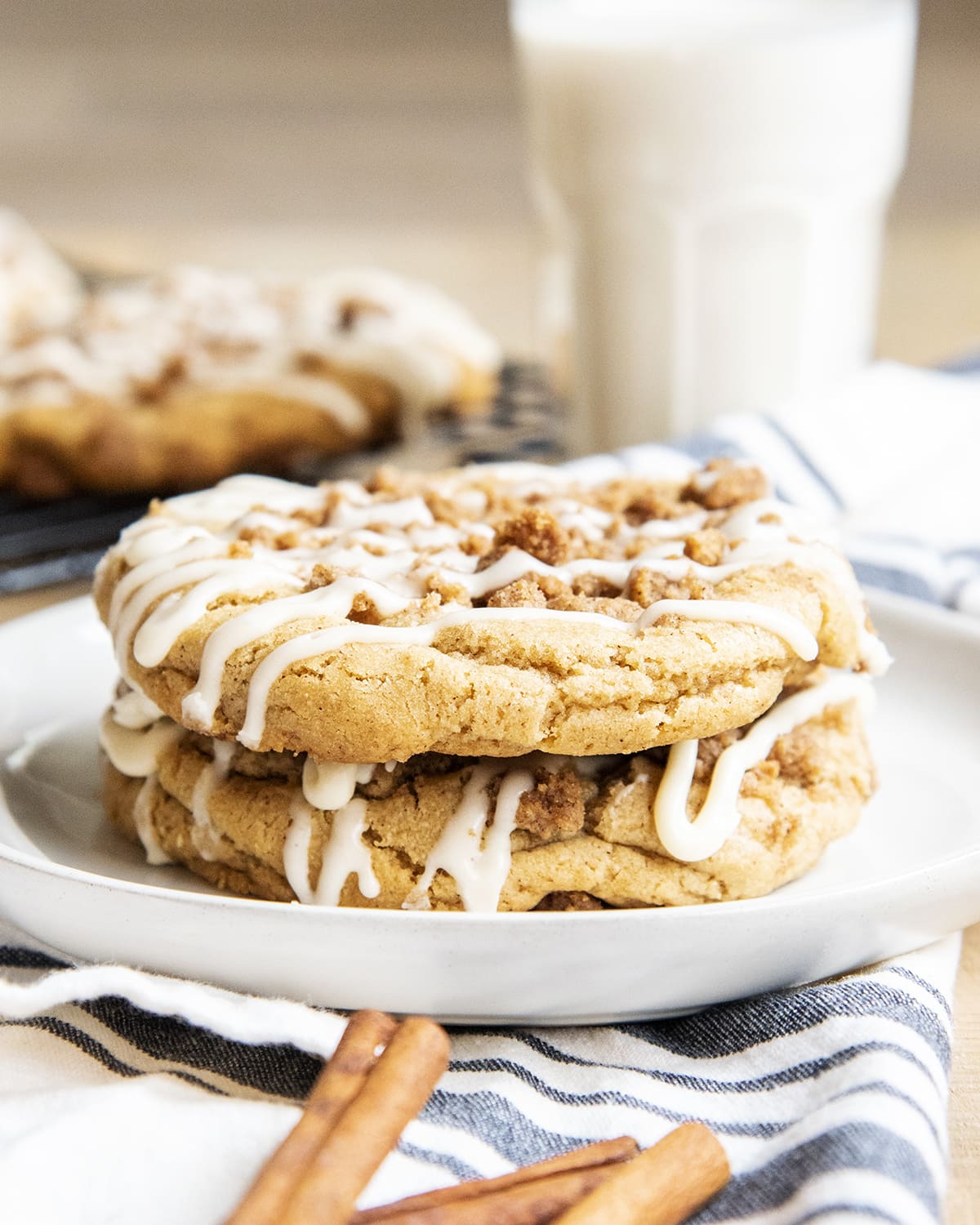 A stack of two coffee cake cookies on a plate, drizzled with icing on top.