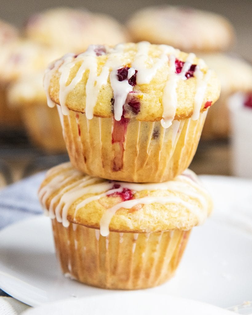 A stack of two cranberry orange muffins with icing drizzled over the top.