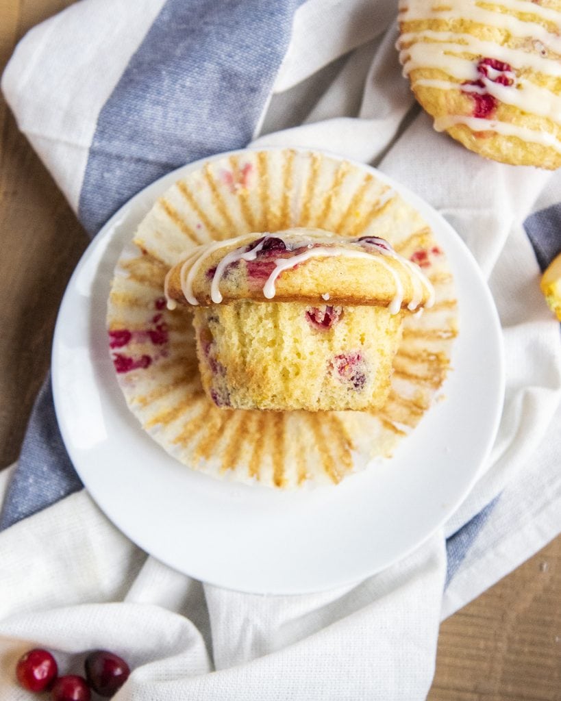 An overhead photo of a cranberry orange muffin laying on a muffin liner on a plate.
