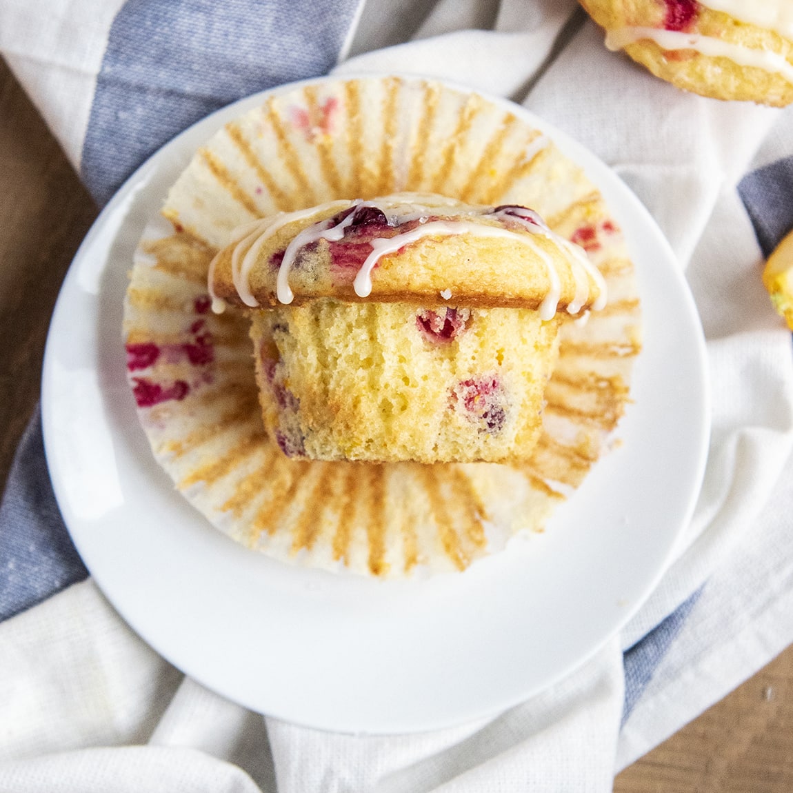 A square image of a cranberry orange muffin on a paper liner on a plate.