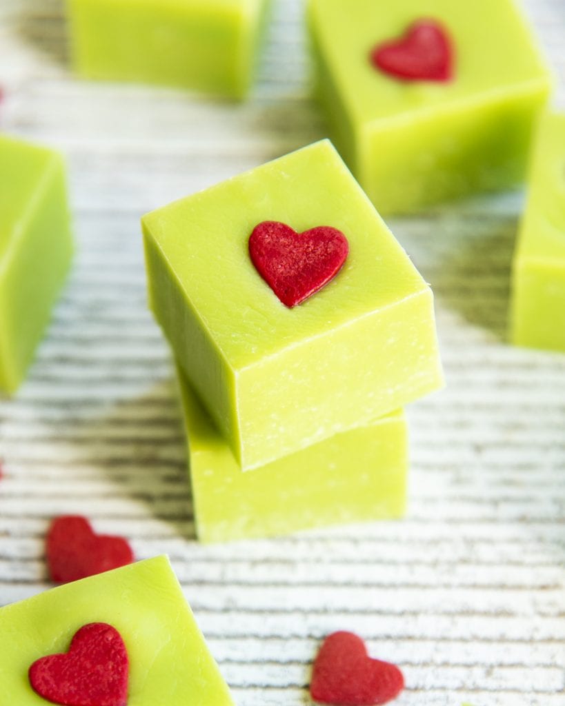 A stack of two pieces of green grinch fudge with heart sprinkles on top.