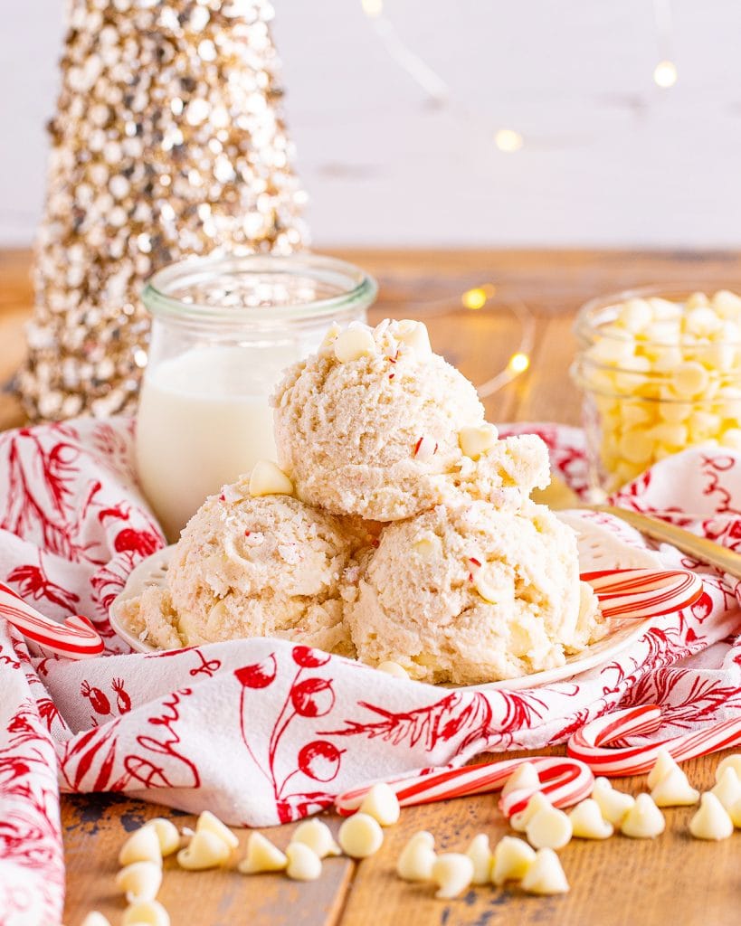 A plate of three scoops of peppermint cookie dough topped with white chocolate chips.