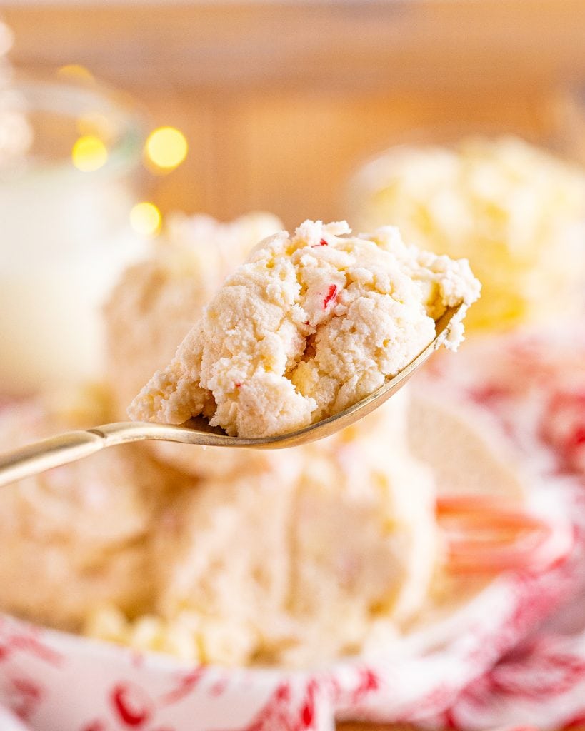 A spoonful of peppermint cookie dough with candy cane pieces in it.