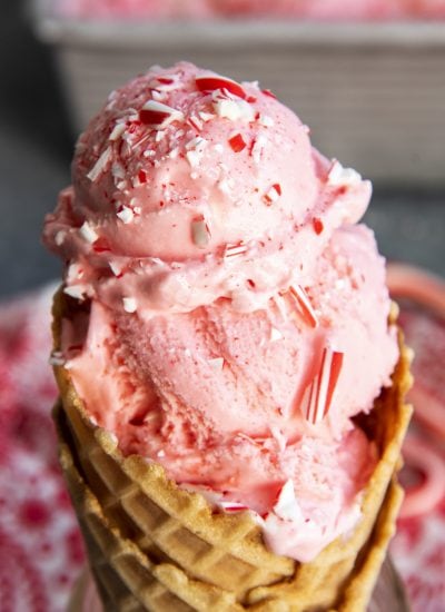 A close up of a peppermint ice cream cone topped with peppermint candy pieces.