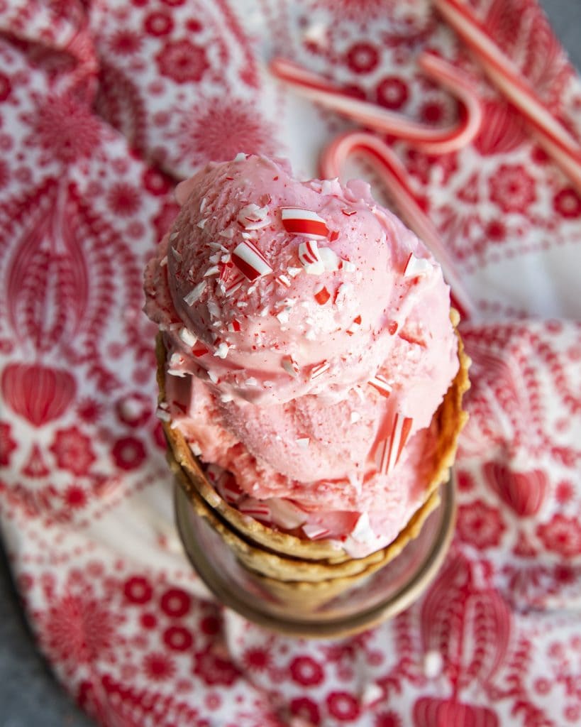 An overhead photo of a peppermint ice cream cone topped with candy cane pieces.