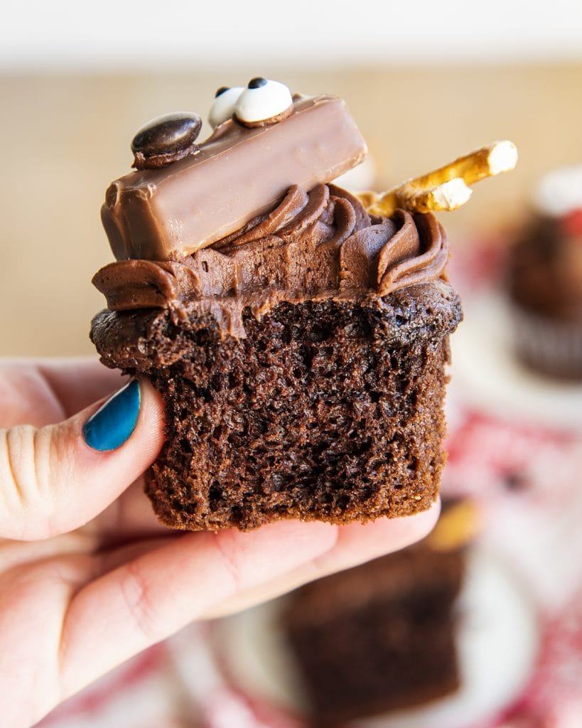 A moist chocolate cupcake topped with chocolate frosting and a candy bar reindeer.