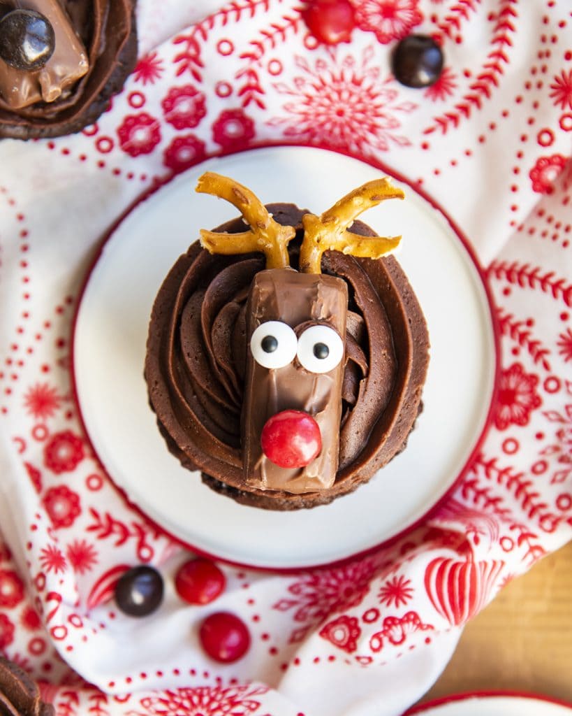 An overhead photo of a chocolate reindeer cupcake topped with a candy bar and pretzel antlers to look like a reindeer.