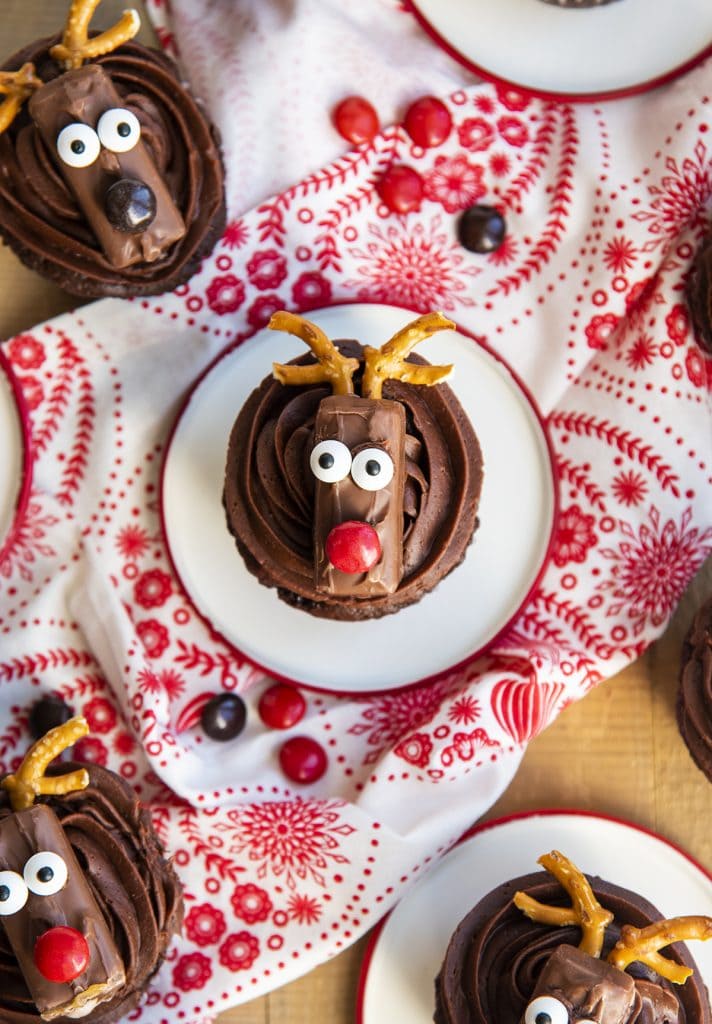 An overhead photo of chocolate cupcakes topped with a candy bar decorated to look like a reindeer.