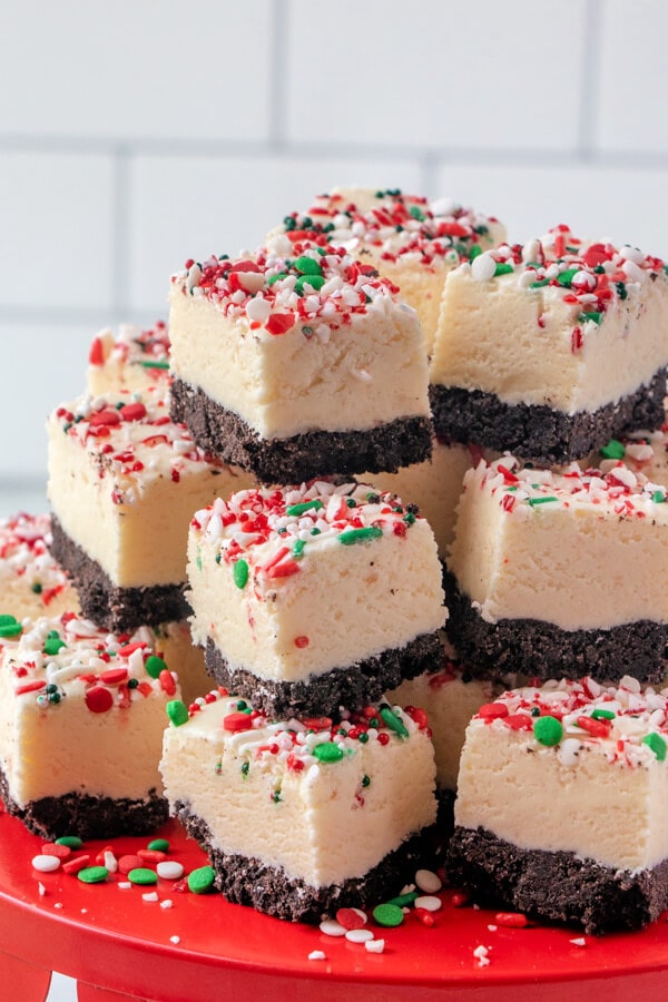 A close up of a pile of pieces of white chocolate peppermint fudge topped with candy cane pieces.