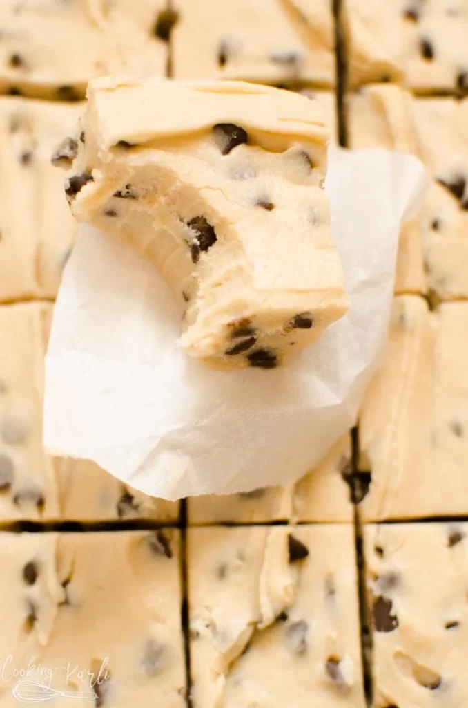 A piece of cookie dough fudge on top of a stack of the fudge. 