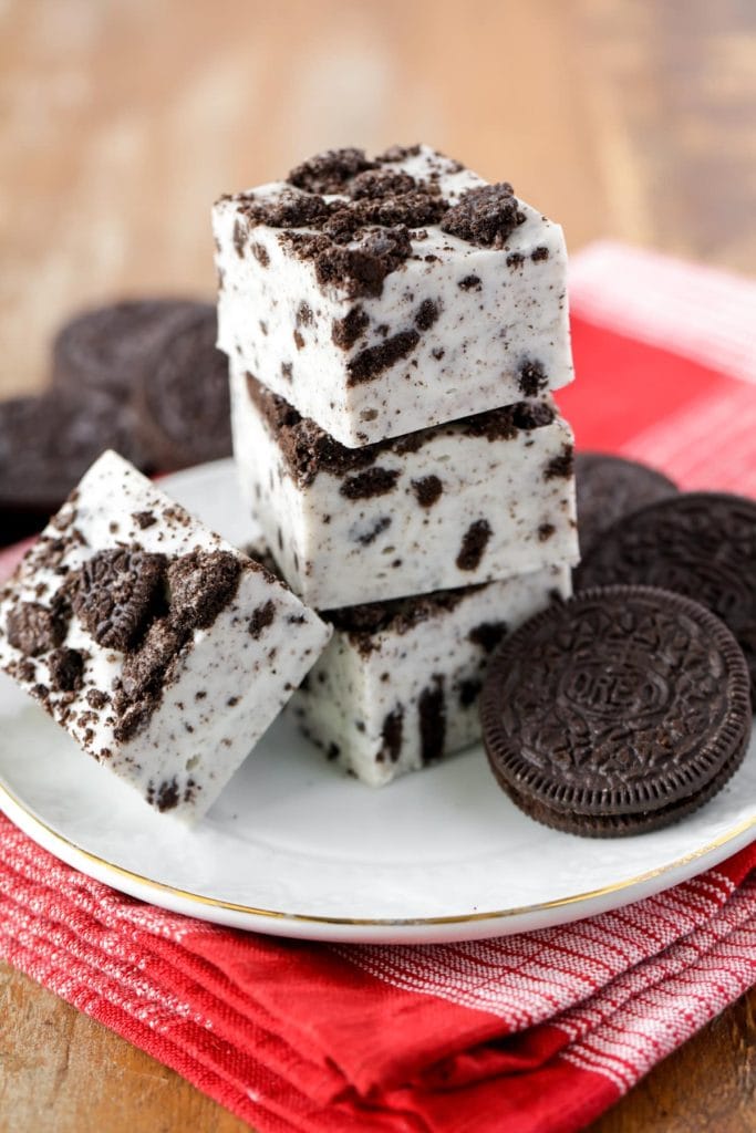 A plate with a stack of three pieces of Oreo filled white chocolate fudge pieces. 