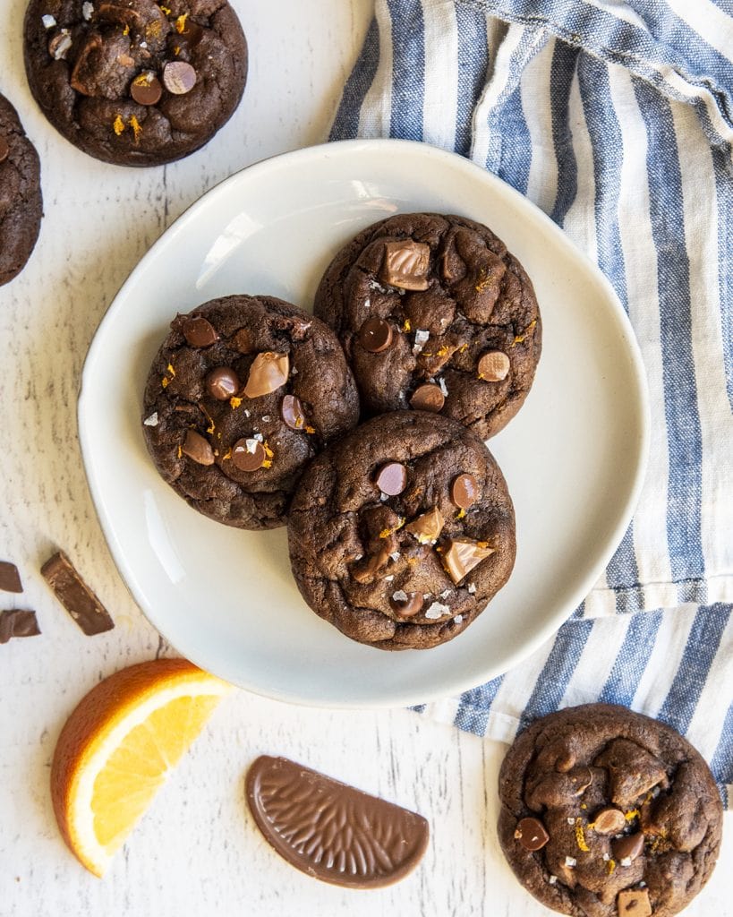 An overhead photo of three chocolate orange cookies on a white plate.
