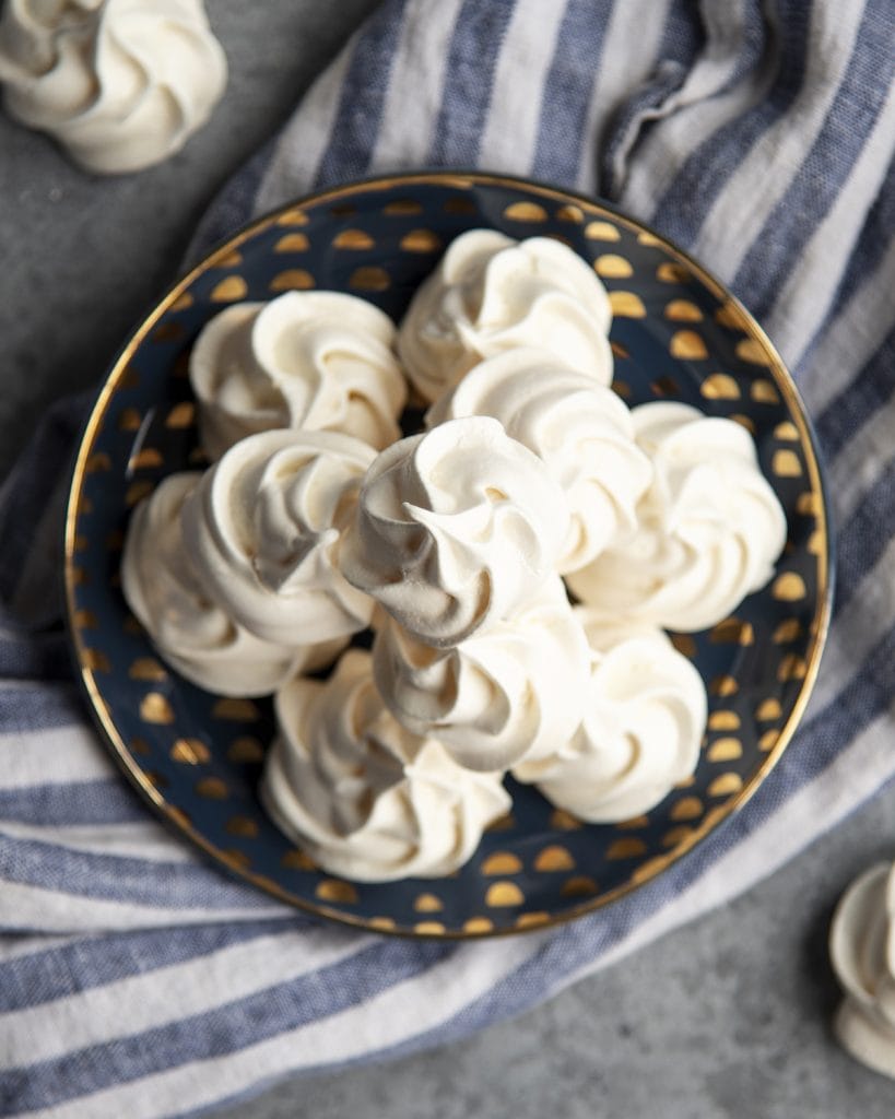 An overhead photo of a plate of stacked meringue cookies.