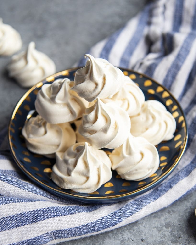 A blue plate topped with a pile of meringue cookies.