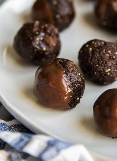 A close up of a chocolate, nut energy ball, dipped halfway in chocolate.