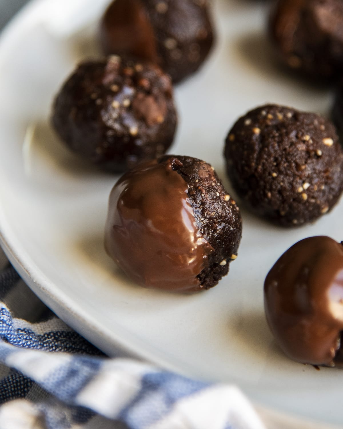 A close up of a chocolate, nut energy ball, dipped halfway in chocolate.