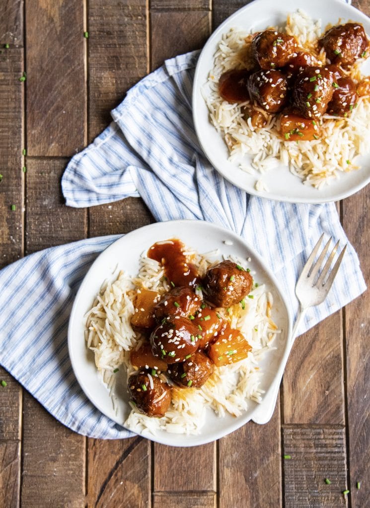 An overhead photo of two plates of rice topped with hawaiian meatballs and pineapple.