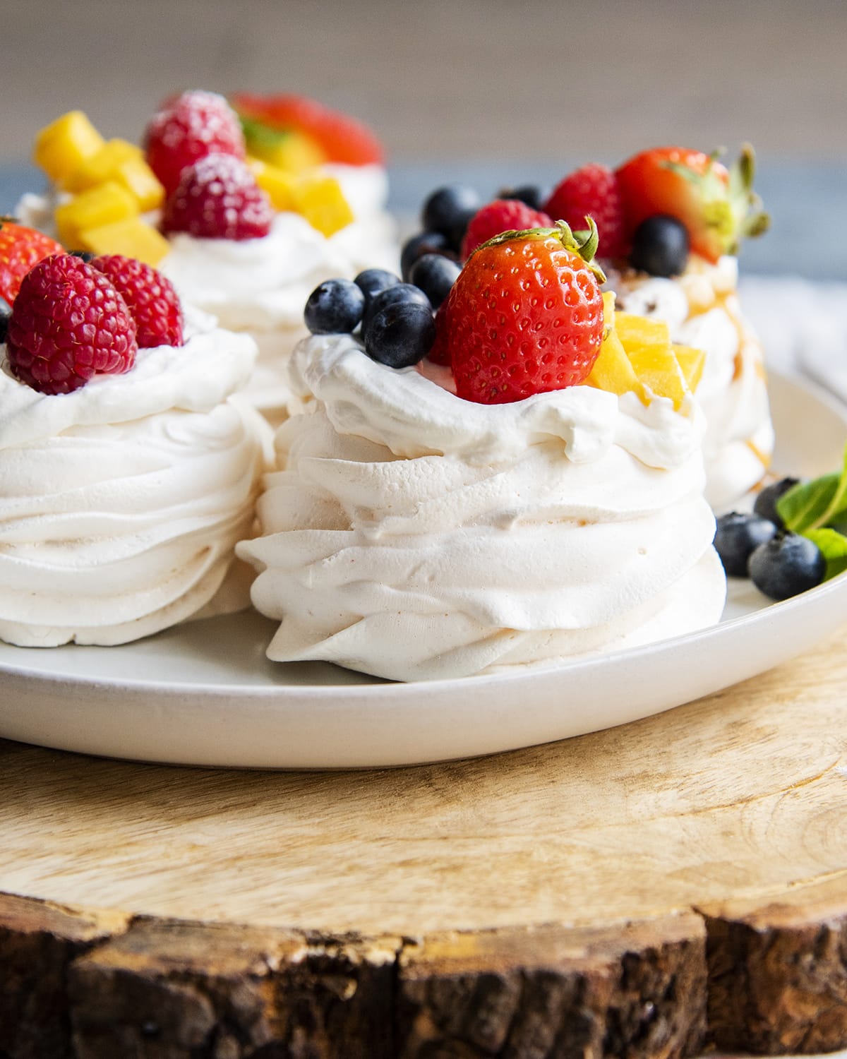 A plate of small pavlovas topped with fruit.