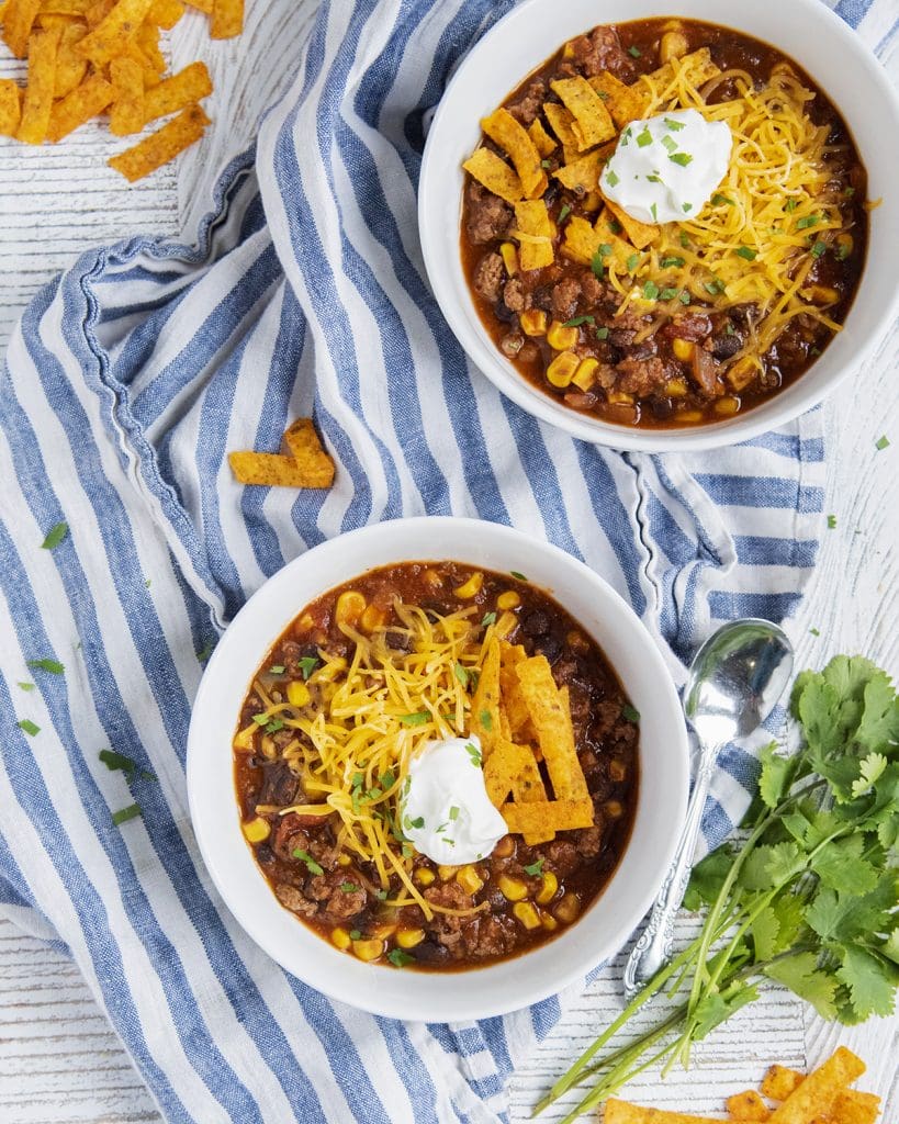 An overhead photo of two bowls of taco soup with cheese on top.