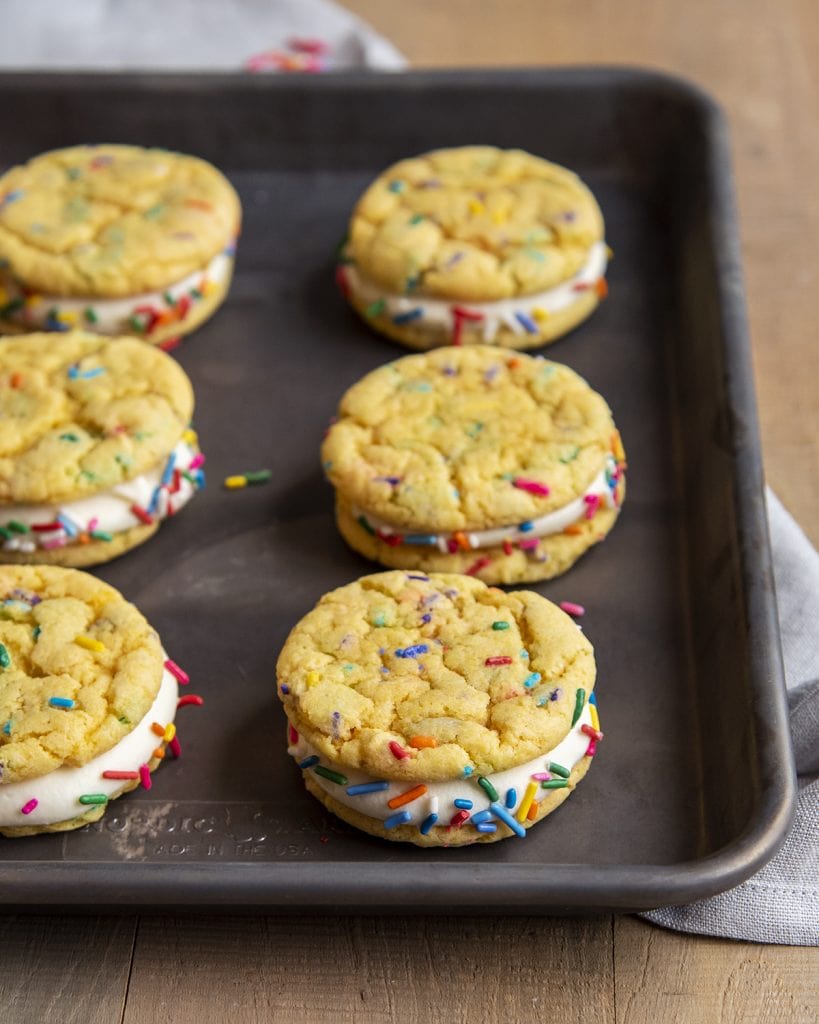 Cake Mix Funfetti Sandwich cookies with cream cheese frosting in the middle, on a cookie sheet.