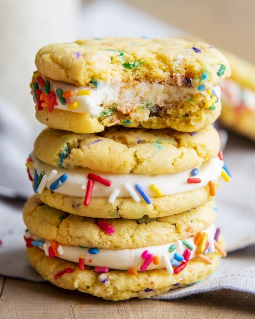 A stack of three confetti sandwich cookies, the top cookie has a bite out of it.