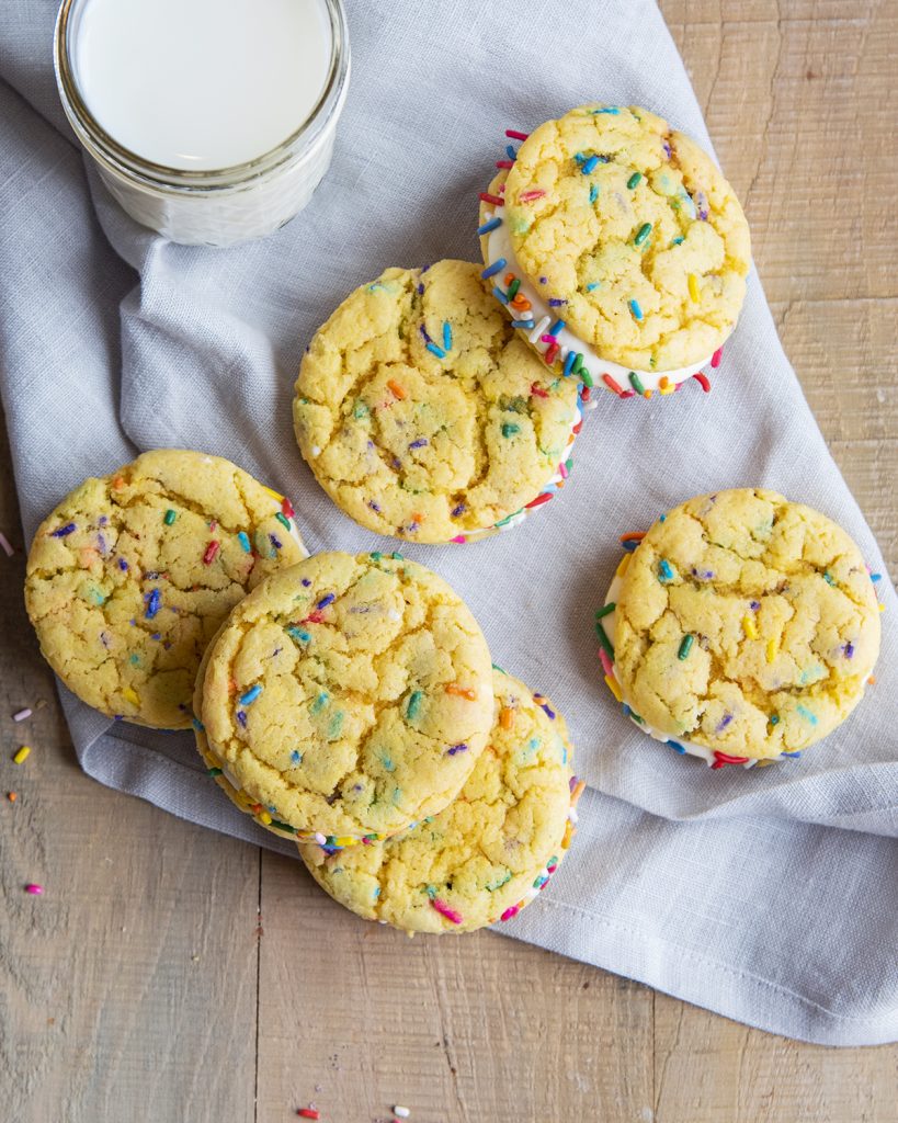 An overhead photo of cake mix confetti sandwich cookies on a grey cloth.