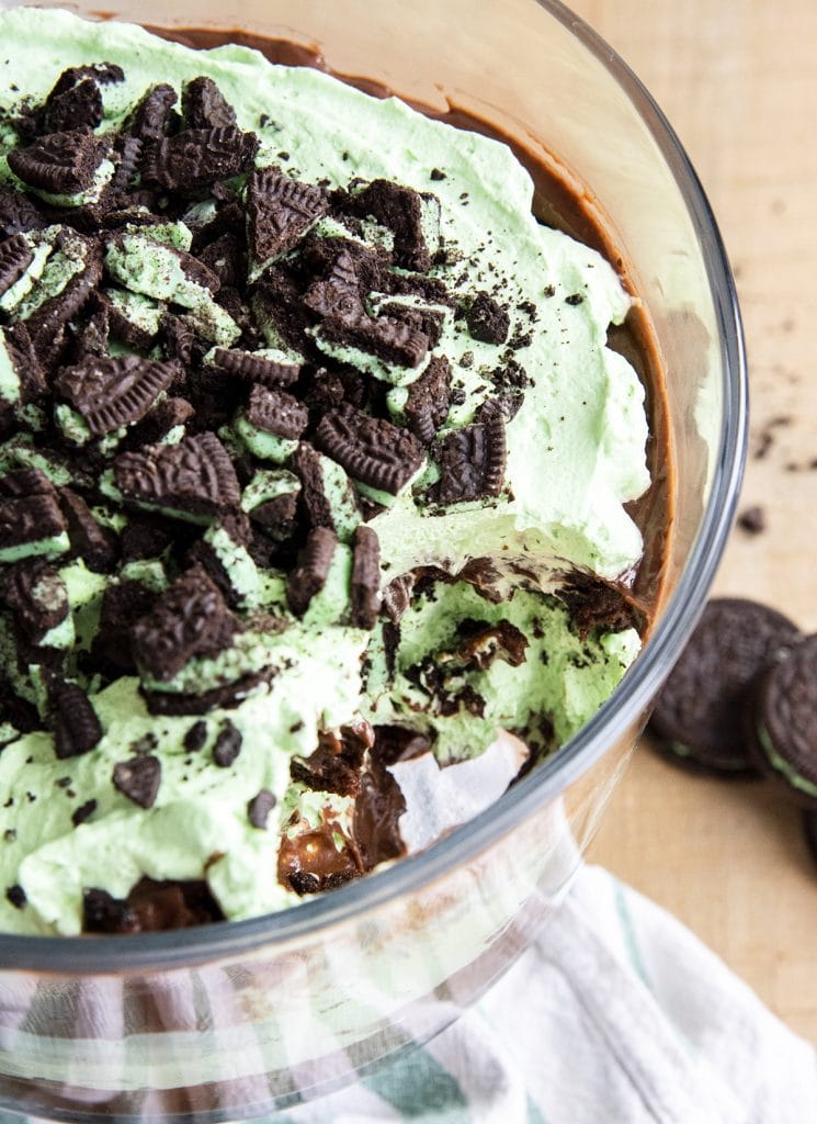 A scoop out of a chocolate and mint brownie trifle topped with mint Oreo cookie pieces.
