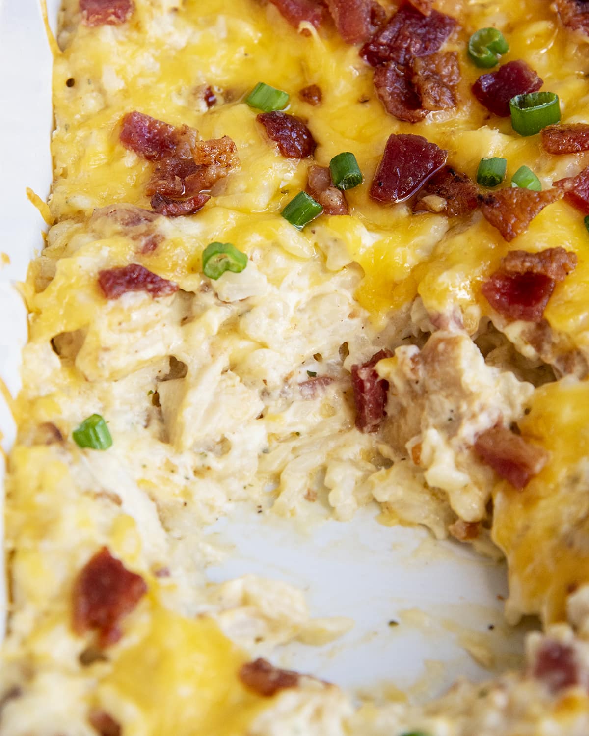 Cheesy ranch chicken and rice casserole in a pan topped with bacon and green onions.